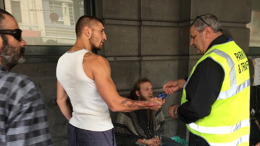 A City of Melbourne worker speaks to homeless people on Flinders Street