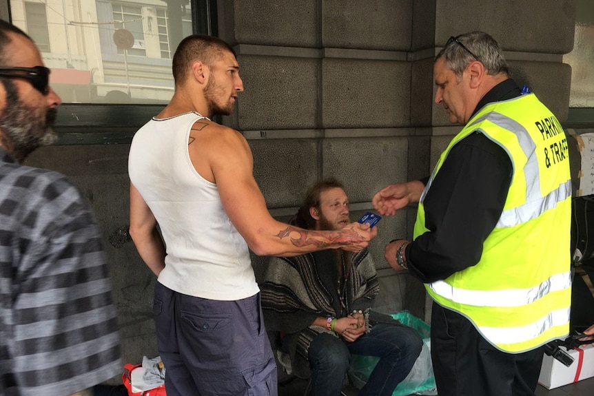 A City of Melbourne worker speaks to homeless people on Flinders Street