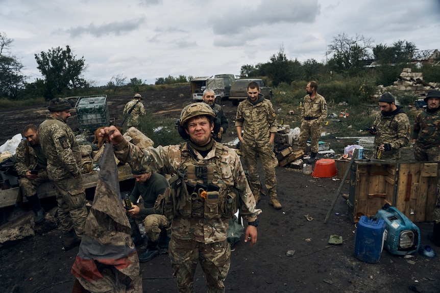 Zdjęcie przedstawiające ukraińskiego żołnierza niosącego resztki rosyjskiej flagi na froncie na Ukrainie 