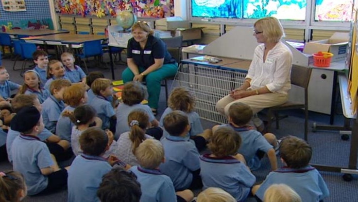 Generic TV still of anonymous Qld primary school children seated on floor of unidentified classroom