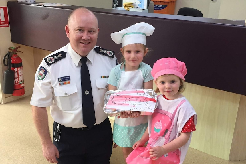 Shane Fitzsimmons poses with two young girls holding cookies