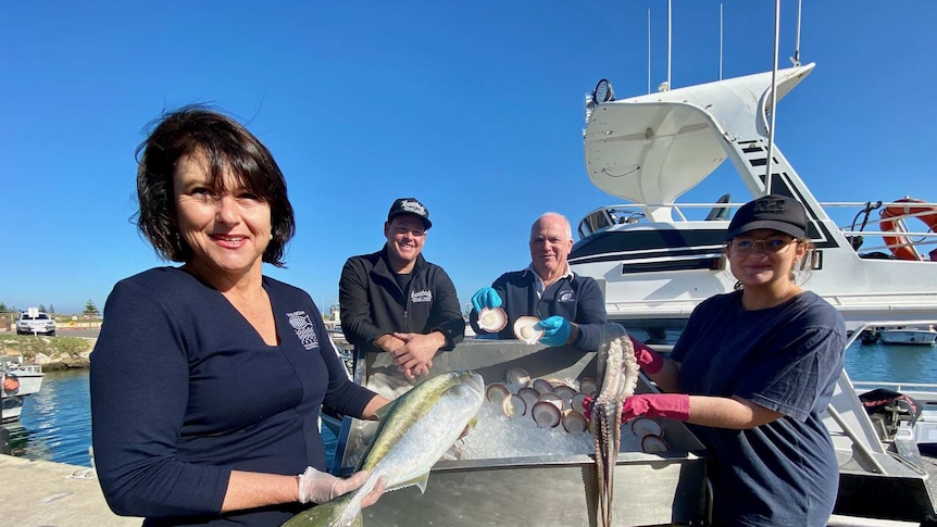 a group of people stand holding seafood