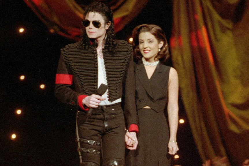 Michael Jackson and Lisa Marie Presley-Jackson stand next to each other on stage