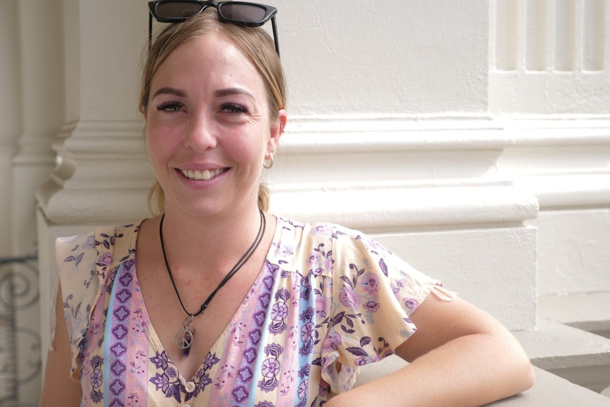 A woman smiles at the camera, white background.