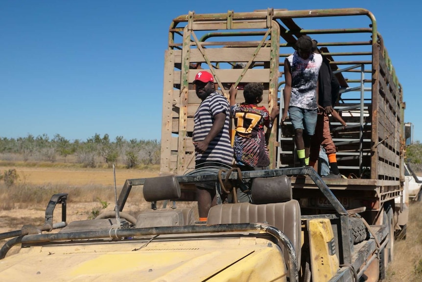 Boys are removing some fencing from a truck on a Top End cattle station.