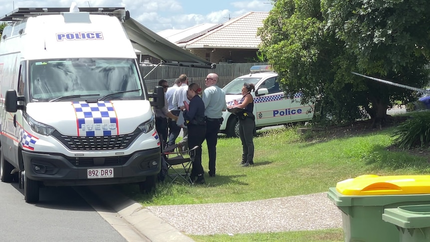 Police gather outside a house. 