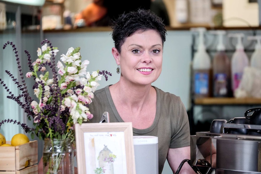 A woman with a coffee machine behind the counter in a cafe