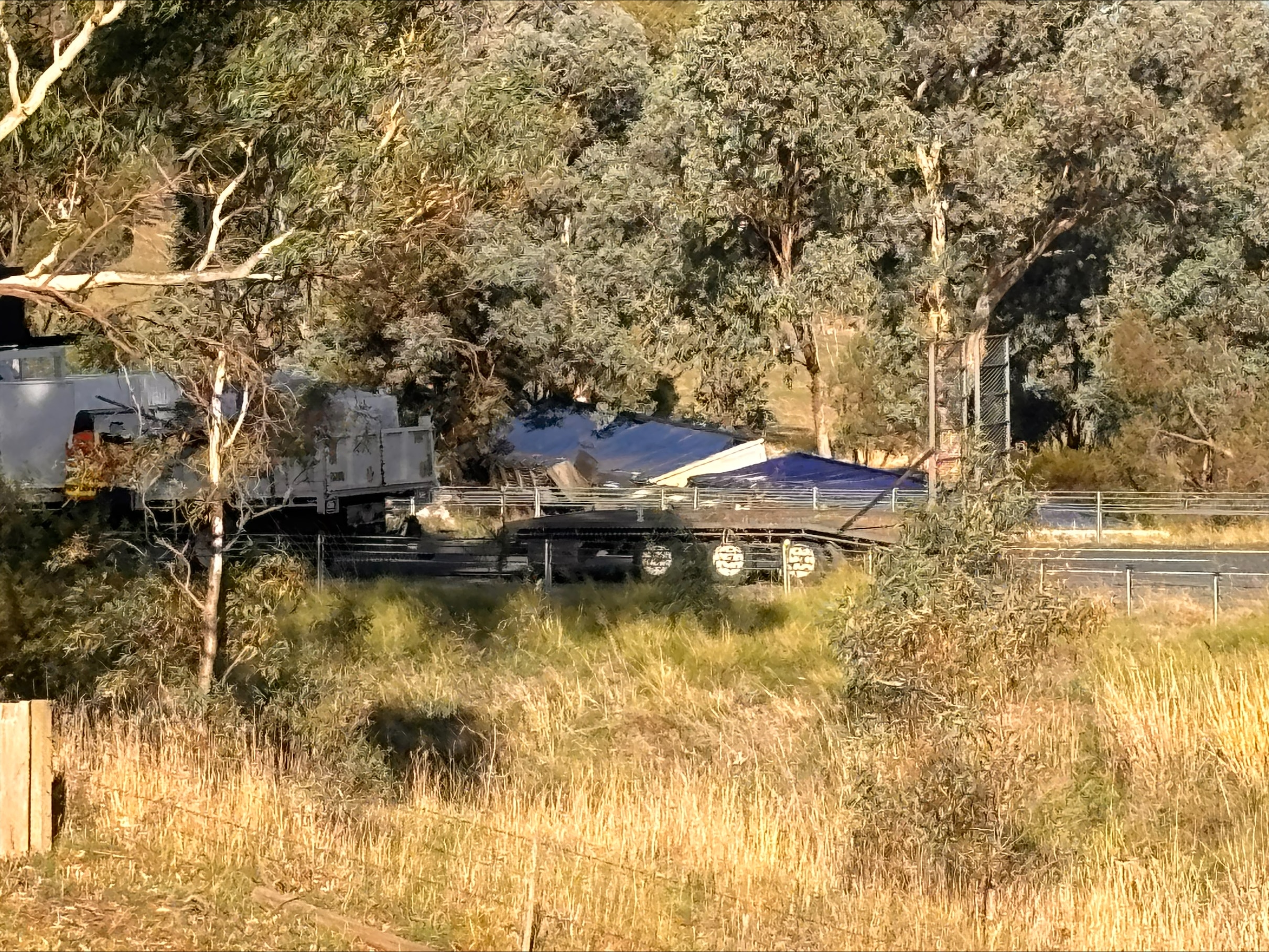 A grassy landscape with a road and a truck on its side