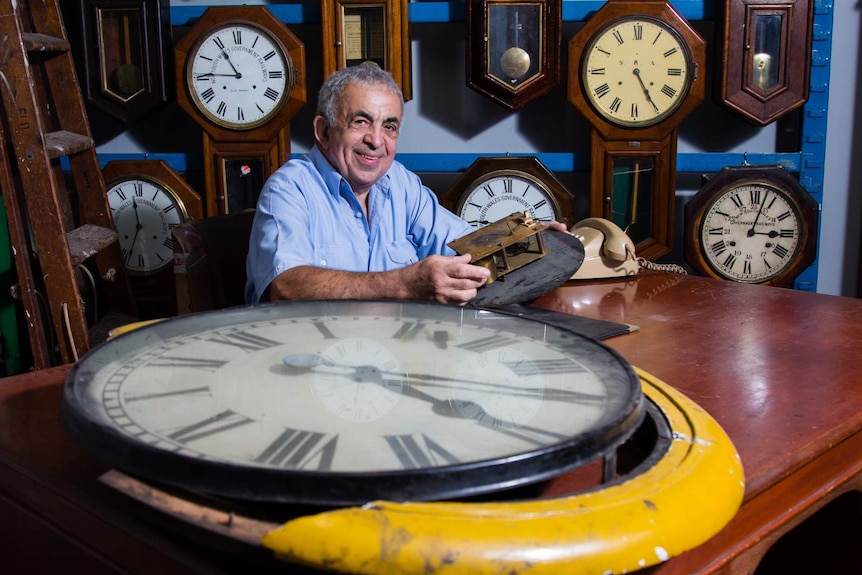 Clock repairer Doug Minty with old mechanical clock face in foreground.