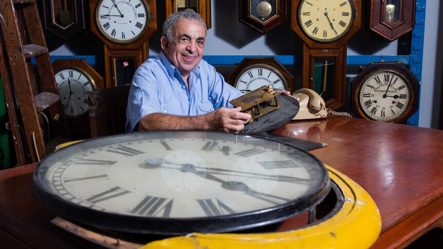 Clock repairer Doug Minty with old mechanical clock face in foreground.