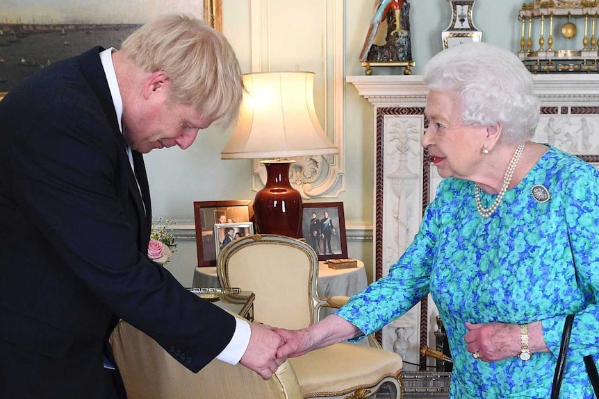 In an ornate room of Buckingham Palace, Queen Elizabeth II shakes the hand of Boris Johnson with a bowed head.