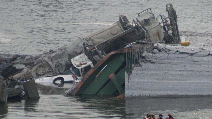 Vehicles lie in the water among the wreckage of the collapsed bridge