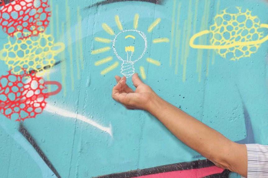 A wall painted with coloured graphics including a central light globe, with a human hand reaching up as if holding it.