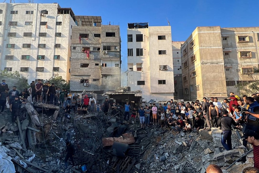 People gather around a crater and rubble from a strike in a residential area in Gaza.