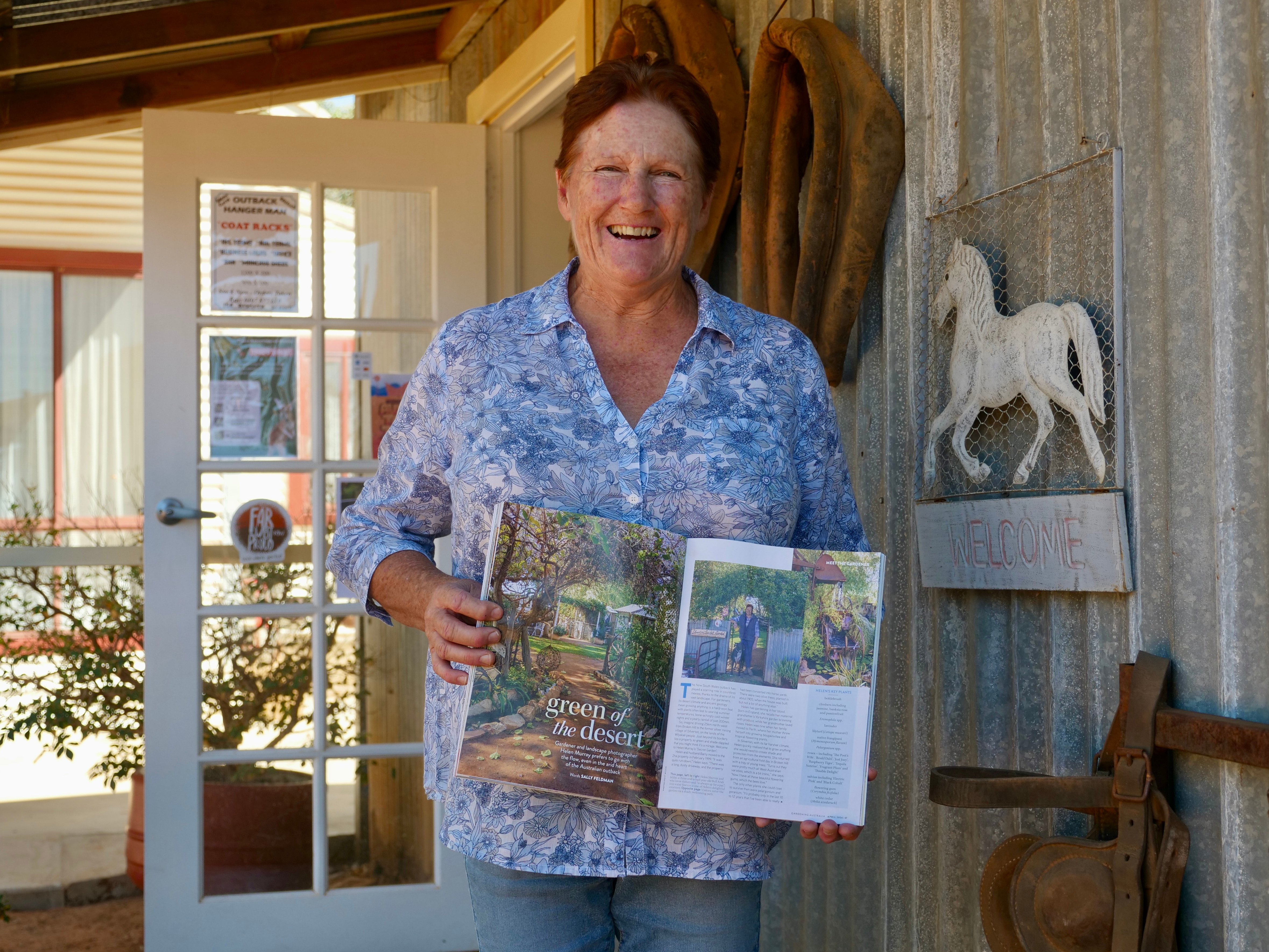 A woman stands holding a magazine.