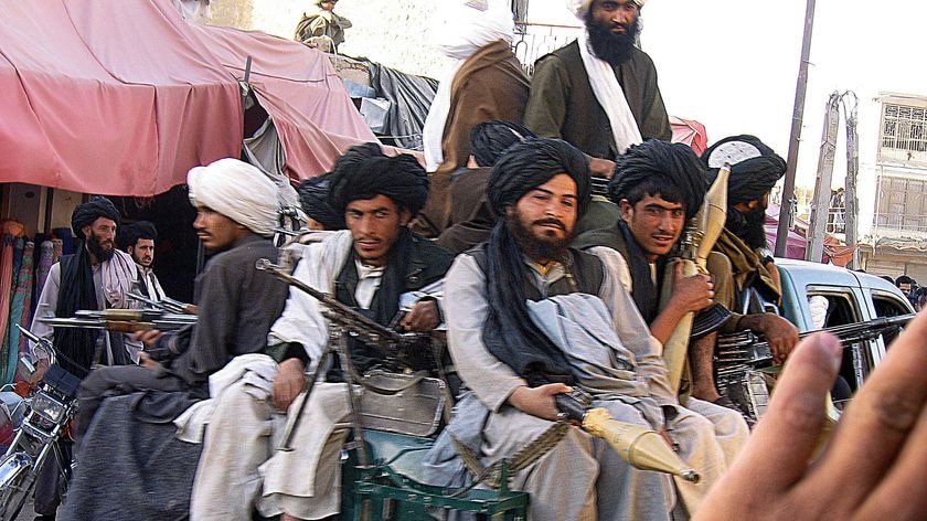 Taliban militans sit on their vehicle