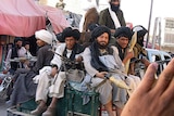 Taliban militans sit on their vehicle