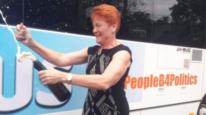 One Nation leader Pauline Hanson cracks open a bottle of bubbly to launch her "battler bus".