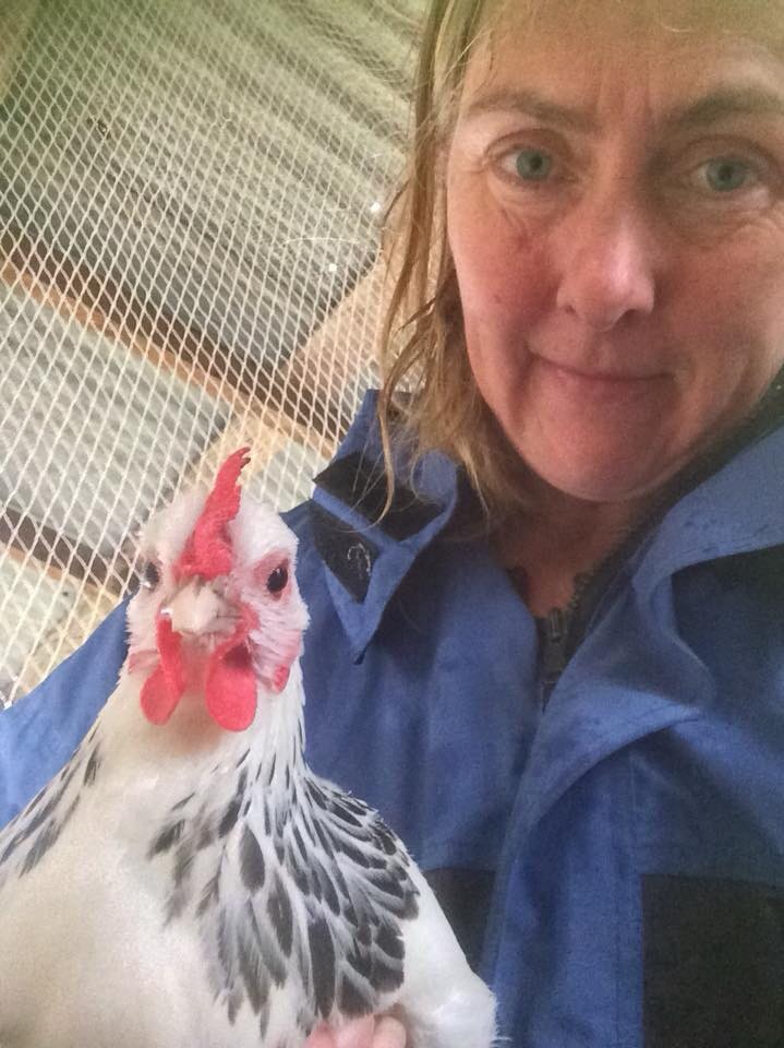 A woman holds a black and white hen.