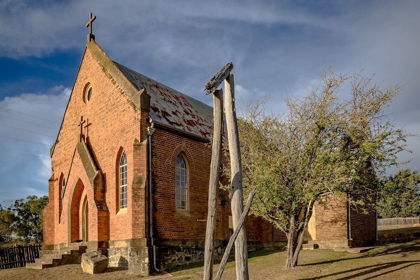 Large brick church with a broken timber fence.