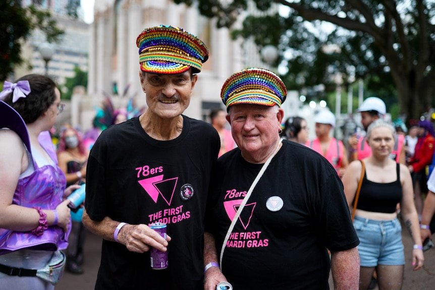 Two men dressed in black t shirts and rainbow hats