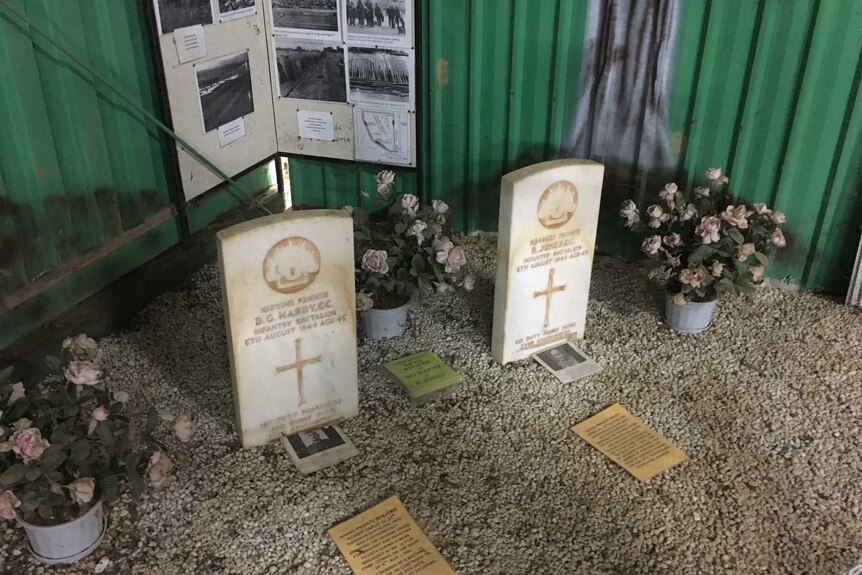 Two white headstones surrounded by photos and flowers.