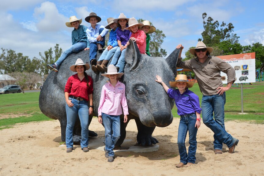 Giant wombat statue with people of varying ages sitting on and standing around it.