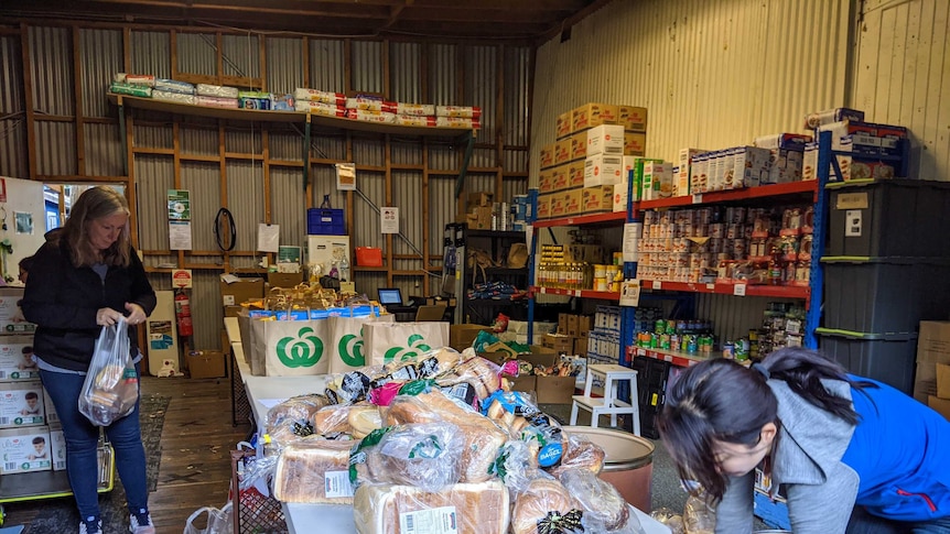 Two women add to a pile of food at a foodbank