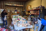 Two women add to a pile of food at a foodbank
