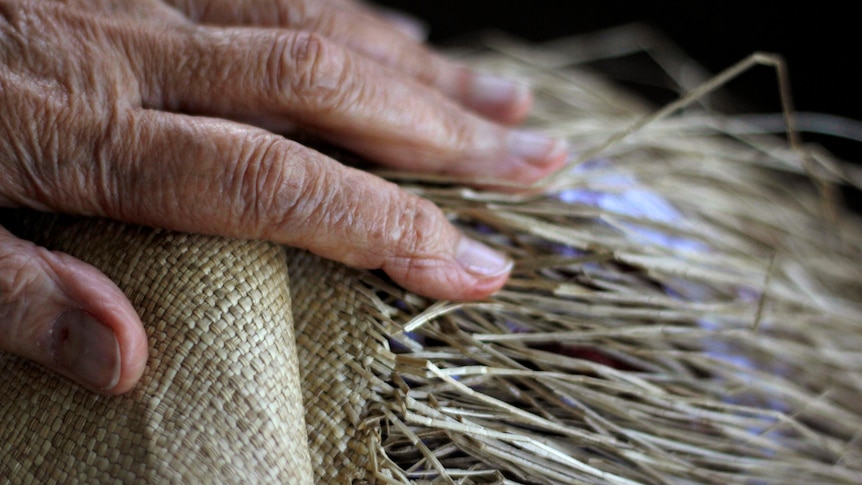 A hand laying on a traditional woven mat