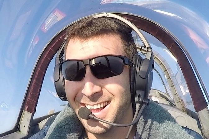A close up photo of a man in a plane cockpit while up in the sky