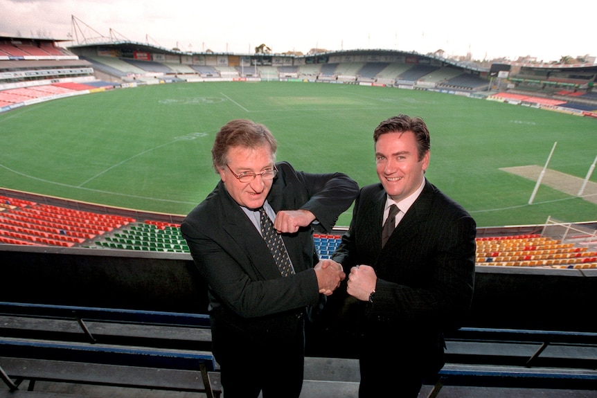 Two AFL club presidents stage a mock fight for the cameras ahead of a match between the two sides at a suburban ground. 