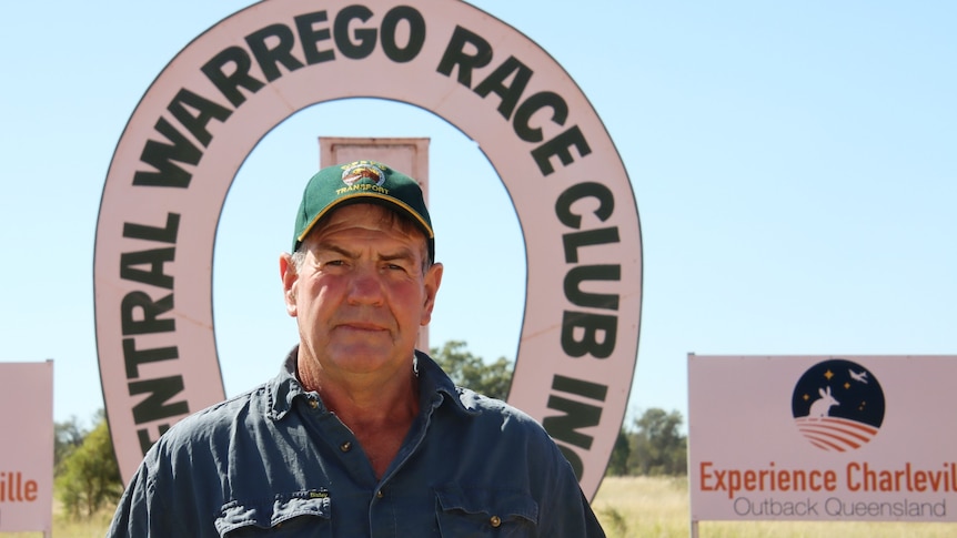 A man in a cap looks at the camera in front of a sign that says Central Warrego Race Club Inc