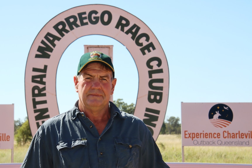 A man in a cap looks at the camera in front of a sign that says Central Warrego Race Club Inc