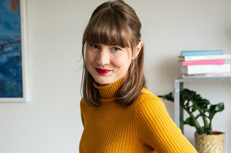 A close-up photo of Lucia Osborne- Crowley, wearing a yellow turtleneck sweater.