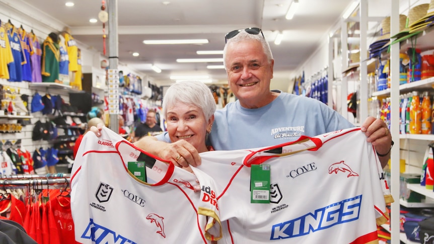 An older couple hold up some Dolphins jerseys.