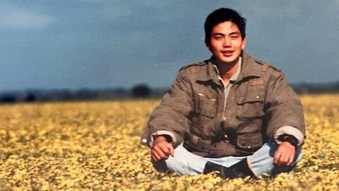 A man sitting in a field smiling.