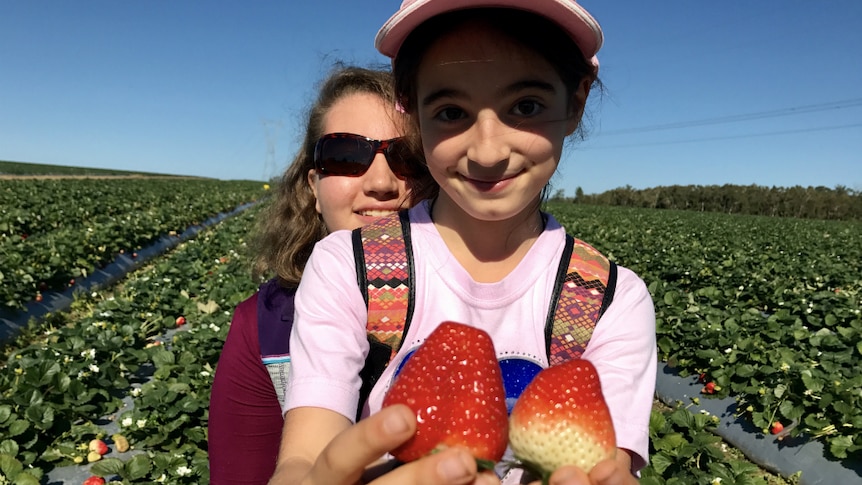 Antonella and Grabriella Coco with two strawberries.