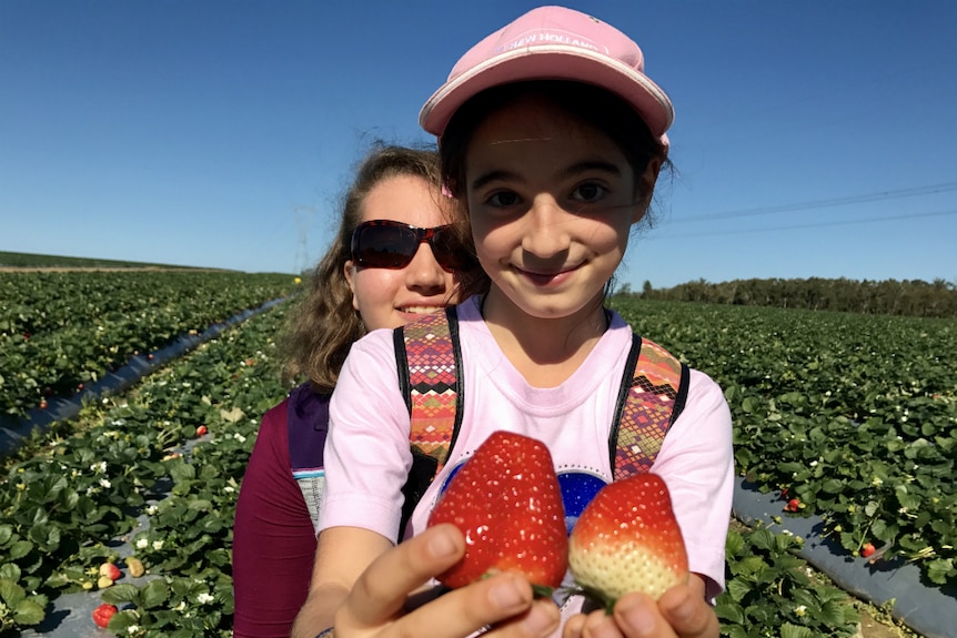 Antonella and Grabriella Coco with two strawberries.