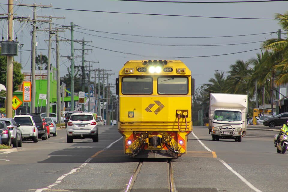 A train travels through the center of a city, with cars driving on either side of it.