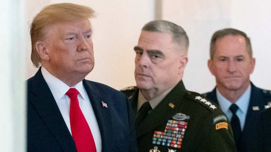 Donald Trump with Mark Milley (centre) and David Goldfein, both of whom are wearing military garb.