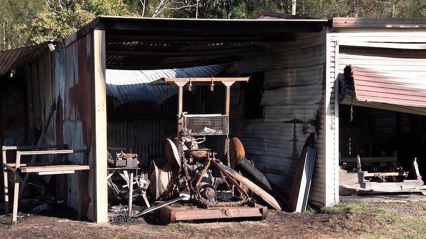 A tractor destroyed by a fire inside a shed which is also badly damaged