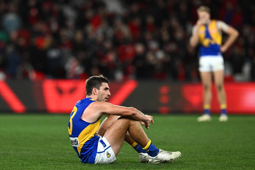 West Coast Eagles player Andrew Gaff sits on the turf looking dejected after a defeat. 