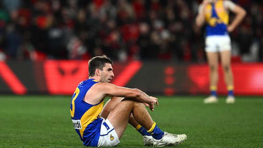 West Coast Eagles player Andrew Gaff sits on the turf looking dejected after a defeat. 