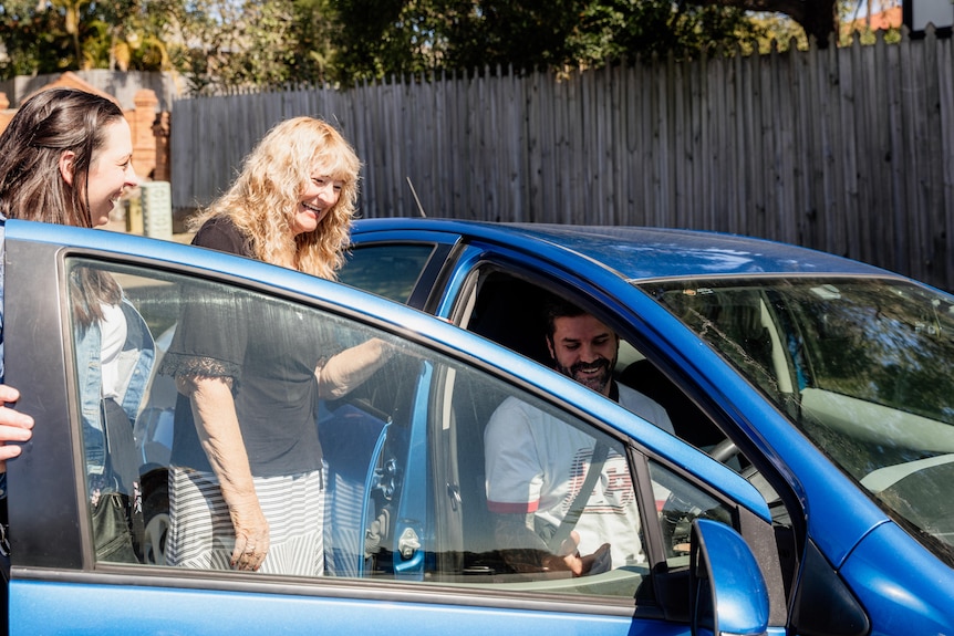 Occupational therapist Jennifer Gribbin holds open the door of the car , with a driver behind the wheel