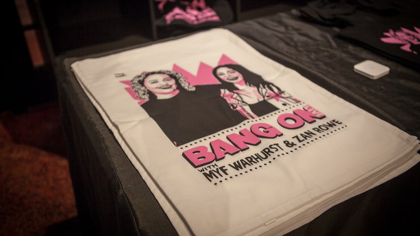 A stack of teatowels displaying a cartoon of Myf and Zan saying Bang On Live