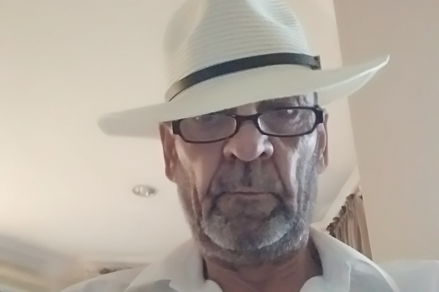 A headshot of Michael Walden wearing a white hat and black-framed glasses.