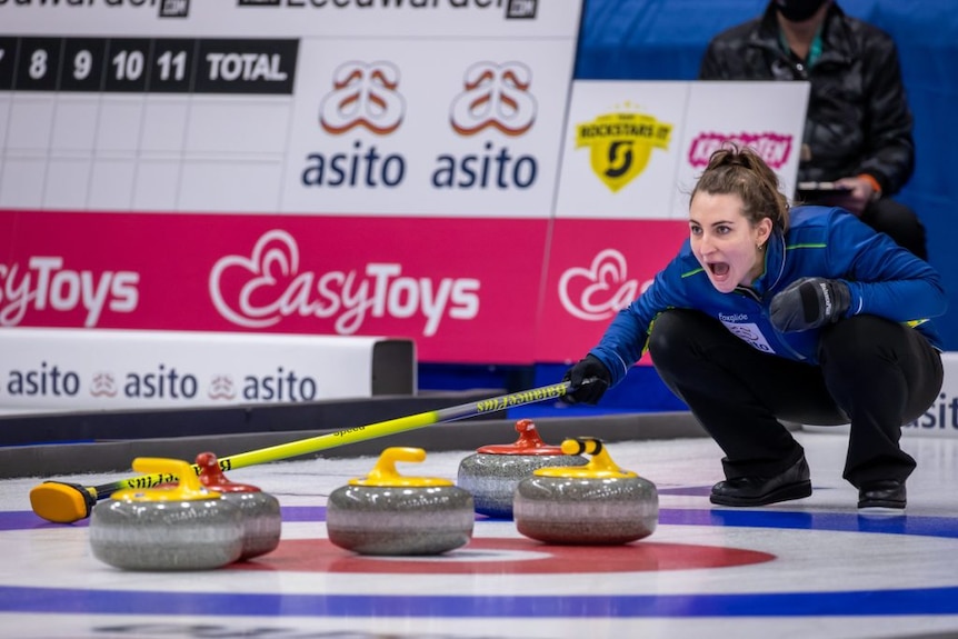 Tahli Gill shouts while crouching down in front of curling stones