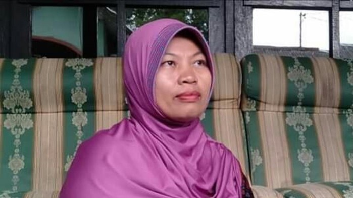 Seorang wanita duduk di lantai bersandar ke sofa