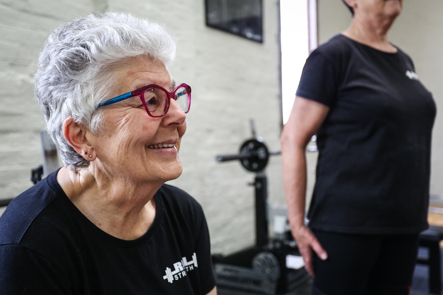 Anne Forden smiles in a gymnasium with gym weights in the background.